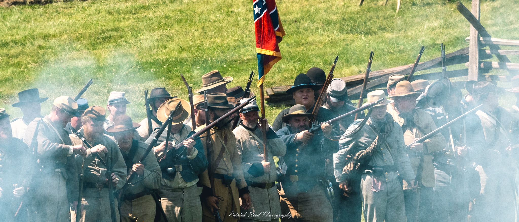 A row of Confederate soldiers firing their rifles, lined up and ready for action. Dressed in gray uniforms, they aim with precision, smoke billowing from the barrels as they engage in battle. Their expressions are focused and intense, capturing the determination and camaraderie of the troops in the heat of conflict.
